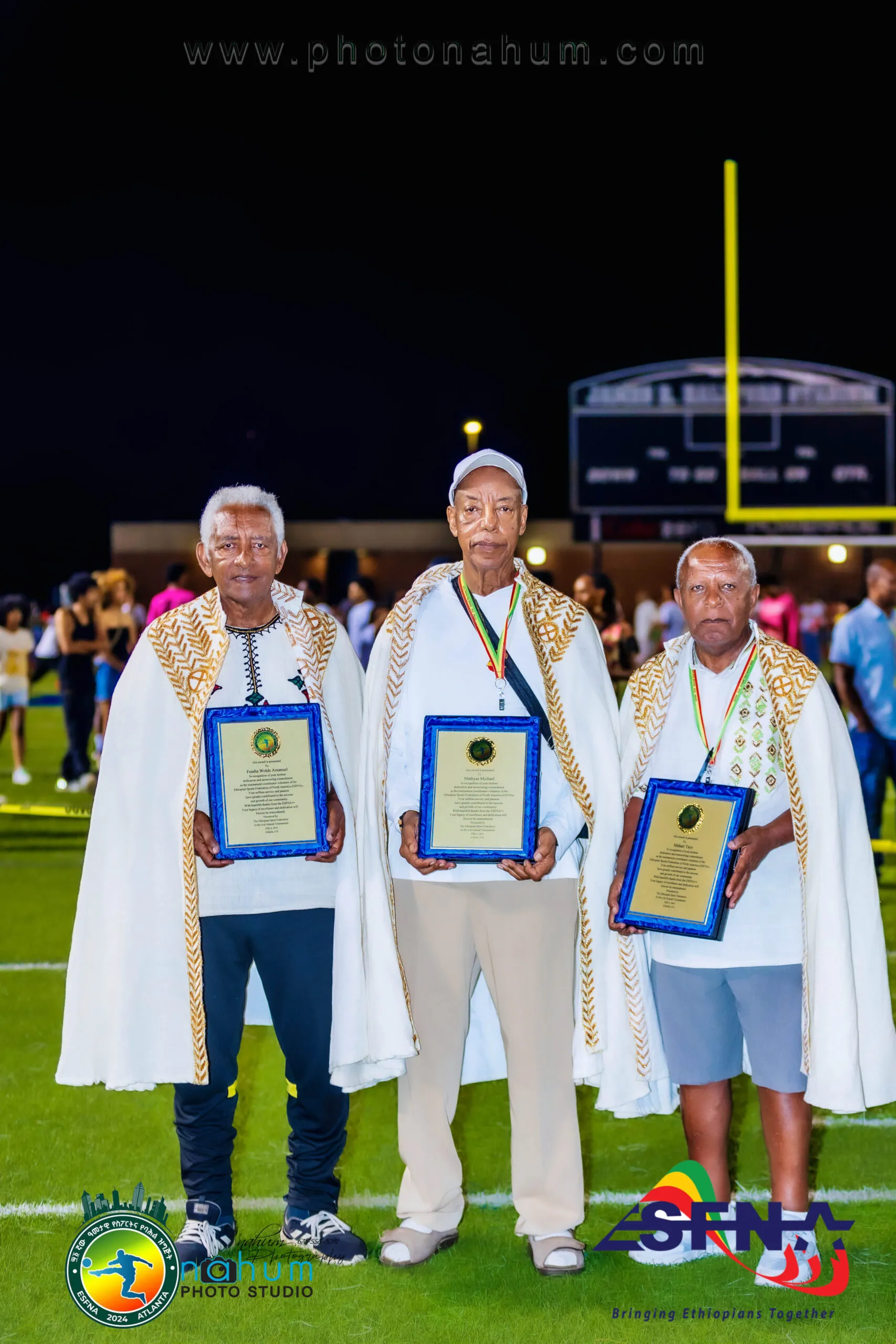 Three honorees in white shawls holding plaques