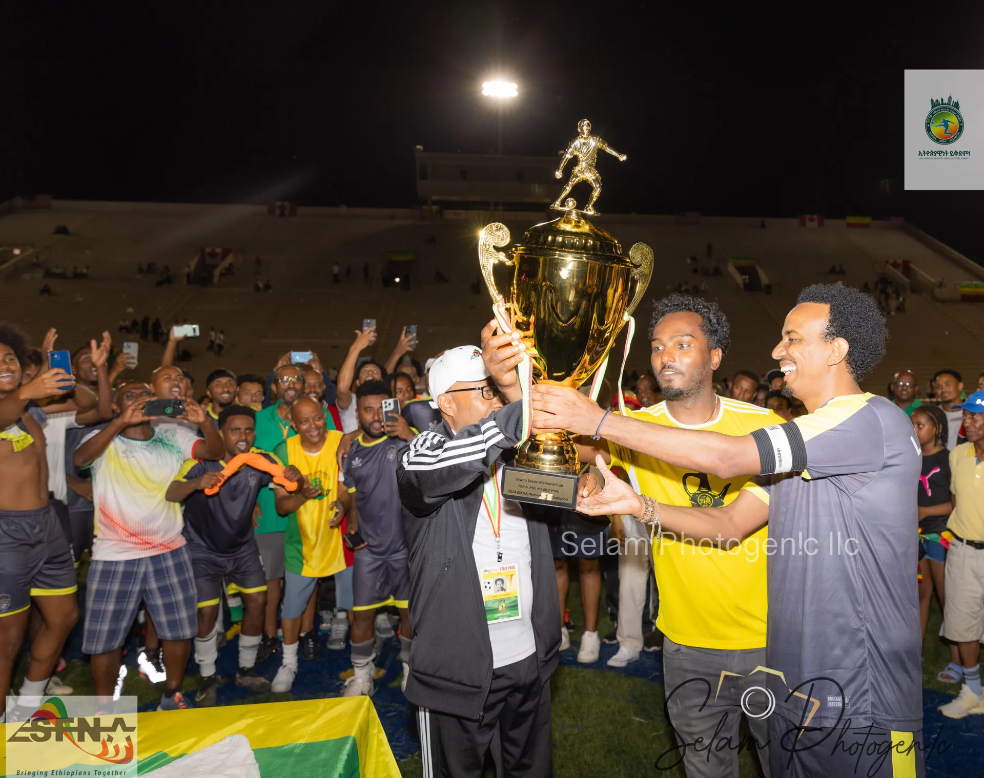Players lifting the trophy under the floodlights